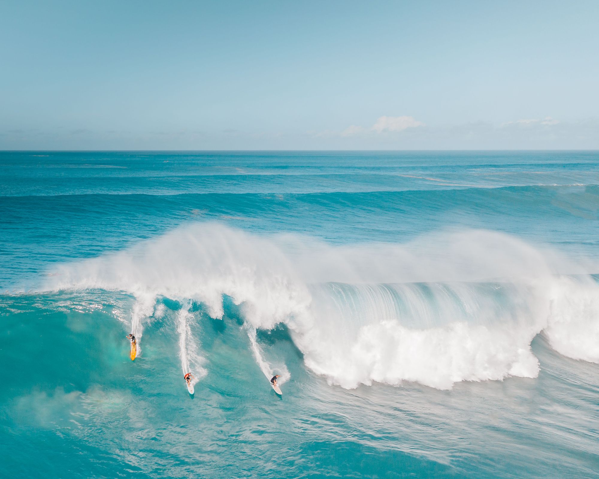 Surfers riding a huge wave at Waimea Bay